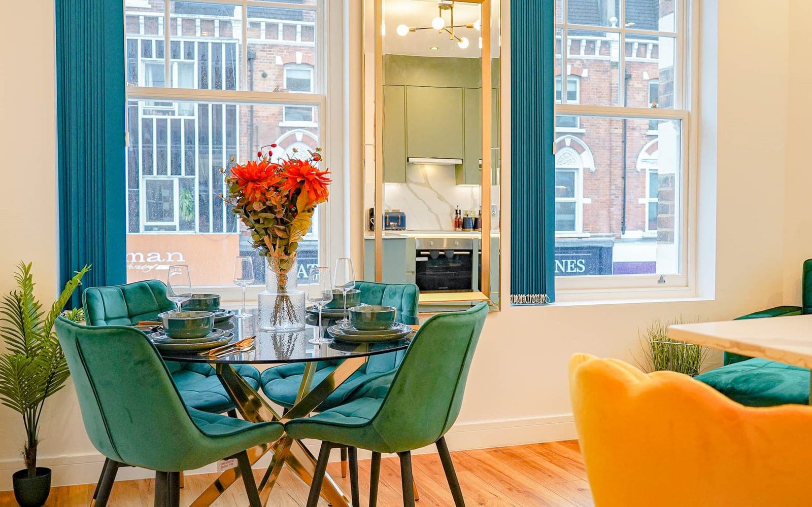 Living room with a green velvet sofa and tall windows at Barnard Mews, London