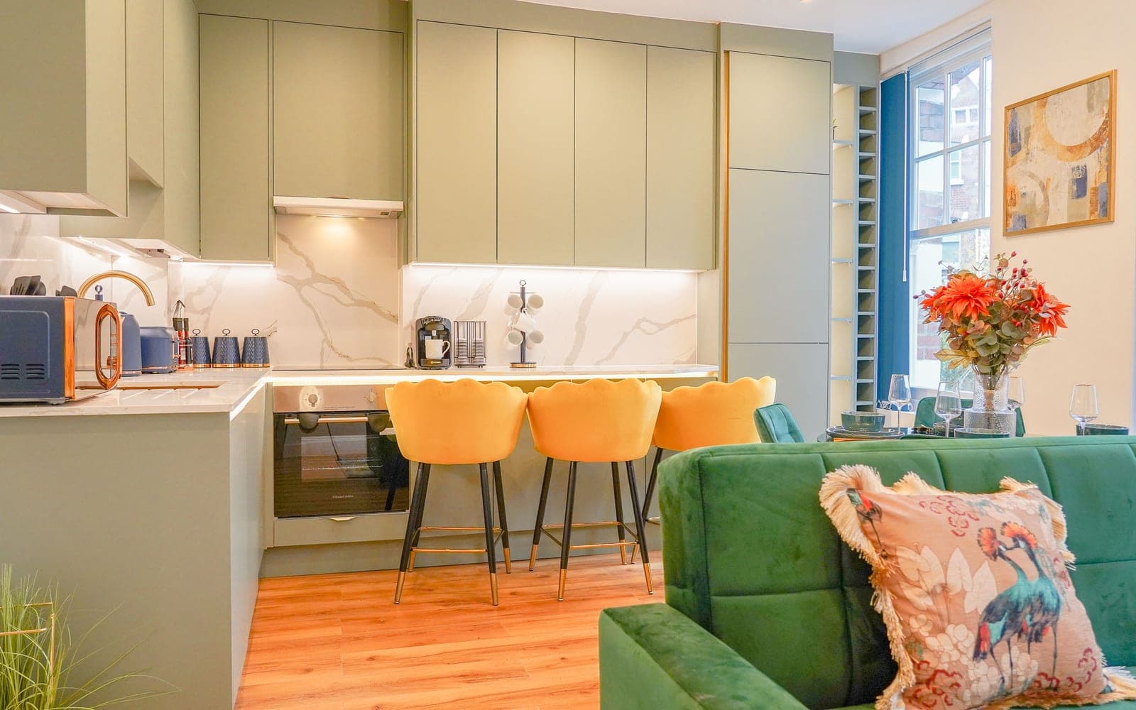 Open-plan kitchen and living room with a green velvet sofa at Barnard Mews, London