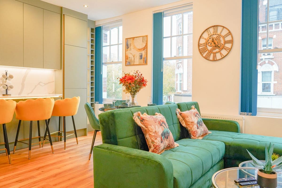 Open-plan kitchen and living room with a green velvet sofa