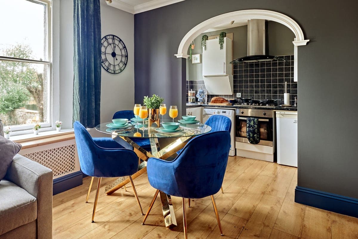 Dining table in a bay window beneath a brass clock